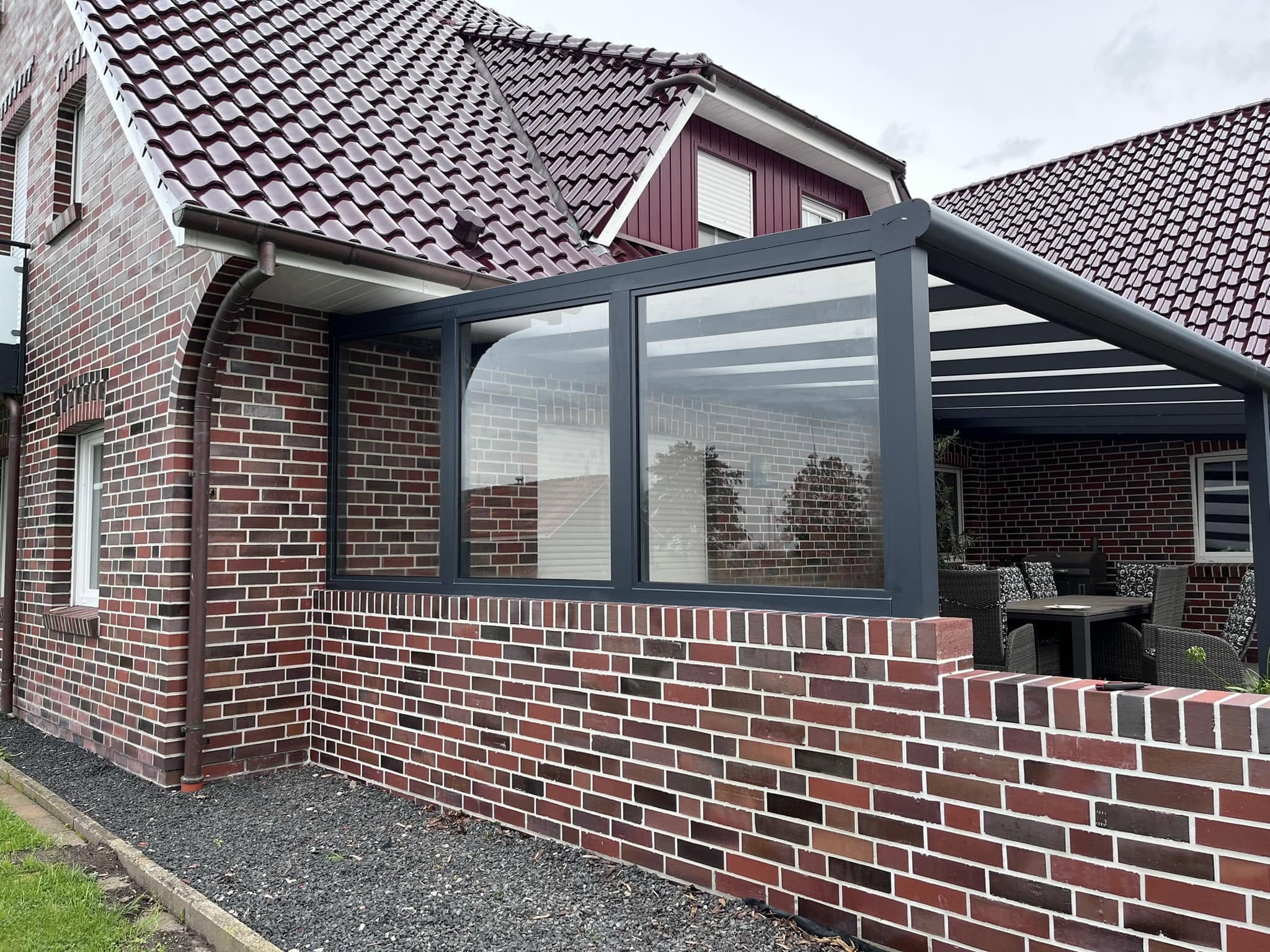 Verglaster Sommergarten-Anbau mit Panoramafenstern an einem Backsteinhaus