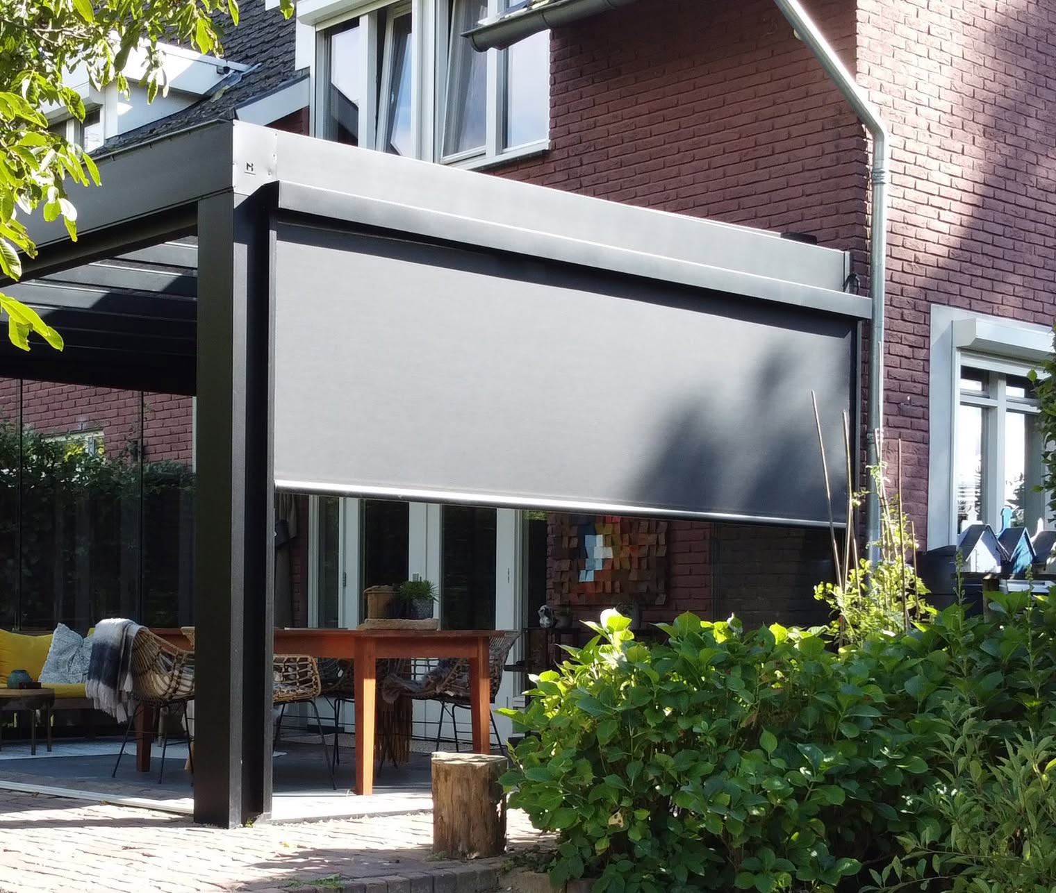 Terrassenüberdachung mit heruntergelassenem Screen als Wind- und Sichtschutz