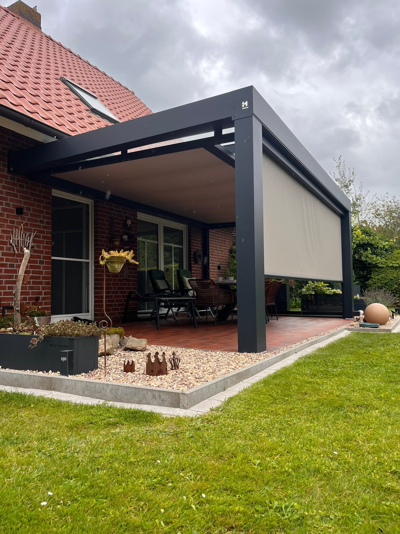Terrassenüberdachung mit Sonnenschutz-Screen in einem gepflegten Garten