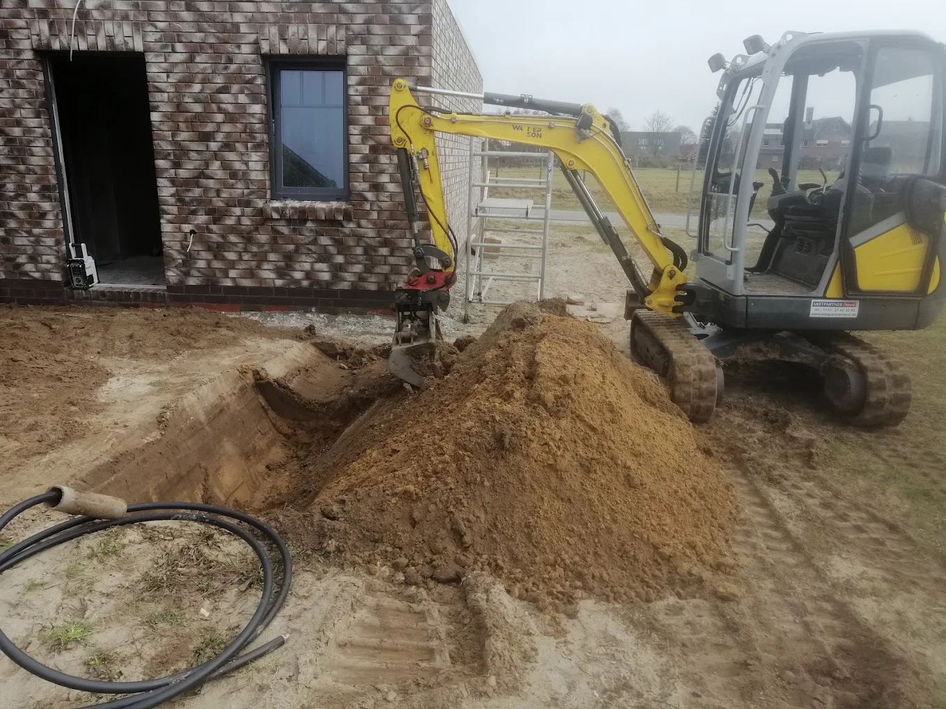 Minibagger bei Erdarbeiten an einem Neubau mit Splittlieferung