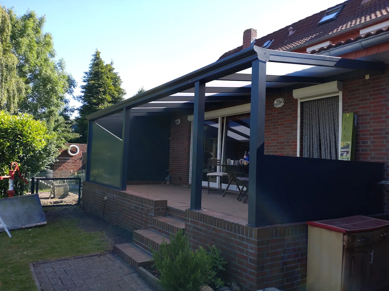 Großes Terrassendach mit Seitenteilen an einem Backsteinhaus