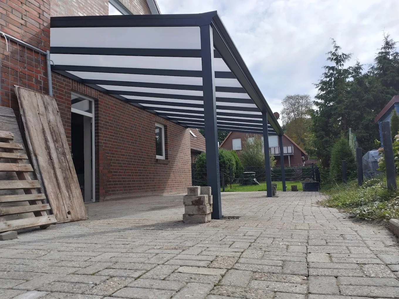 Terrassendach mit elektrischem Sonnenschutz-Screen an einem Backsteinhaus